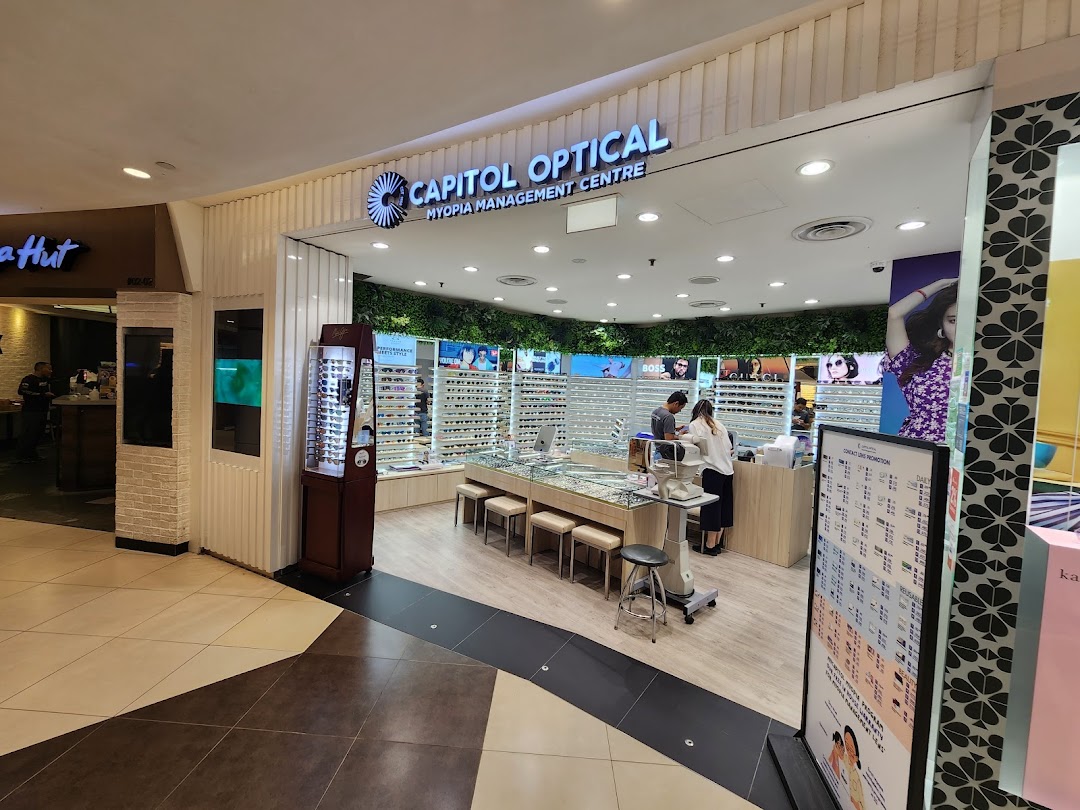 The image shows the bright and modern storefront of Capitol Optical, an optical shop with various eyewear displays.