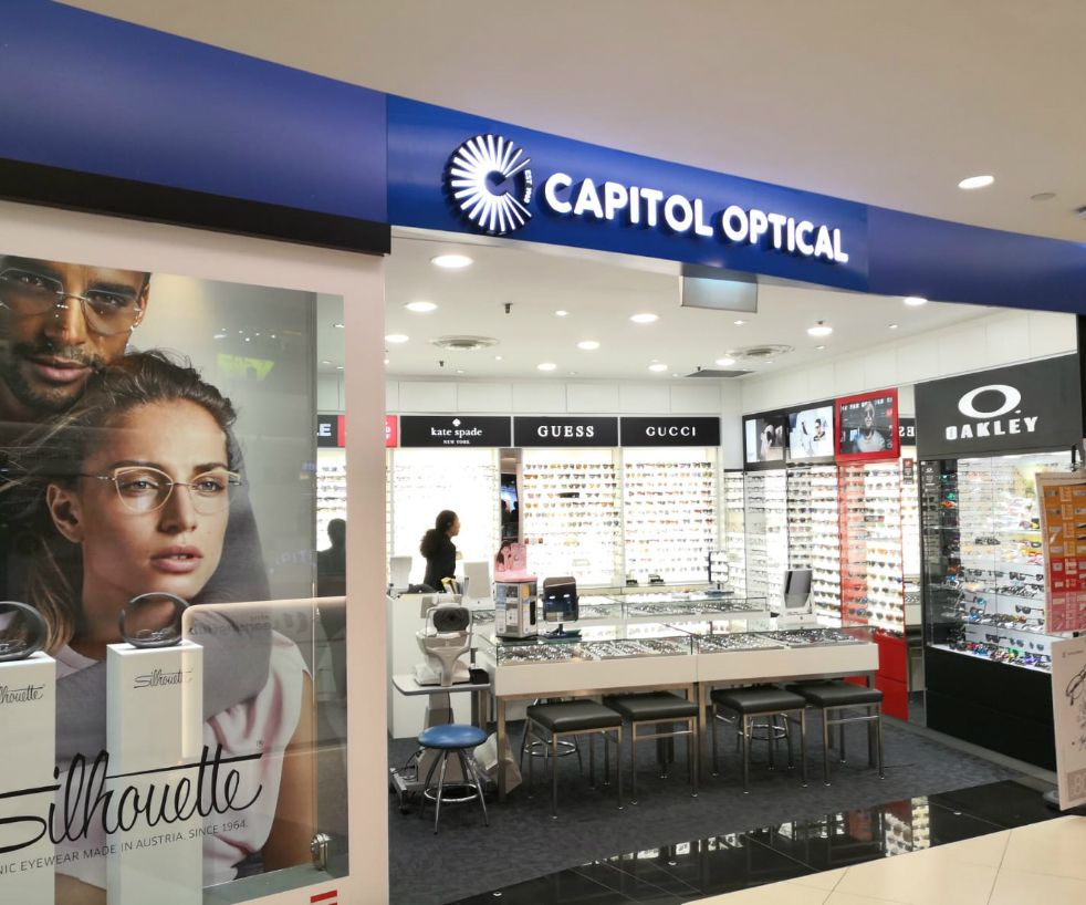 The shop front of Capitol Optical, showcasing a wide range of eyewear from brands like Kate Spade, Guess, Gucci, and Oakley.