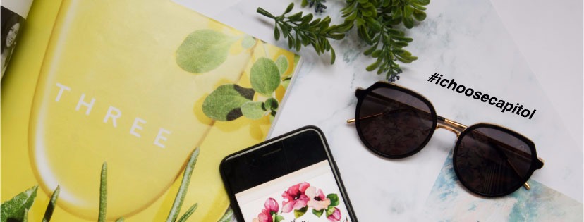 A pair of stylish sunglasses, a smartphone, and a magazine on a marble-patterned surface.