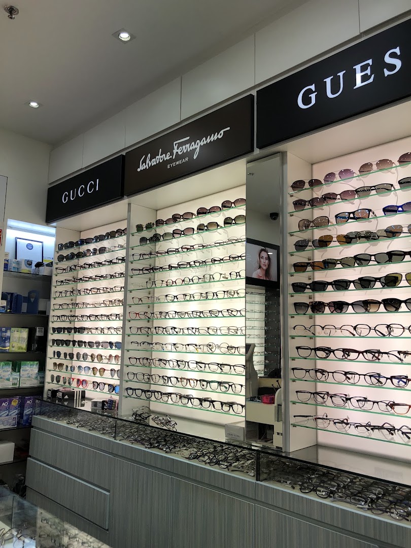 An optical shop interior showcasing a wide selection of eyeglasses and sunglasses from brands like Gucci, Salvatore Ferragamo, and Guess.