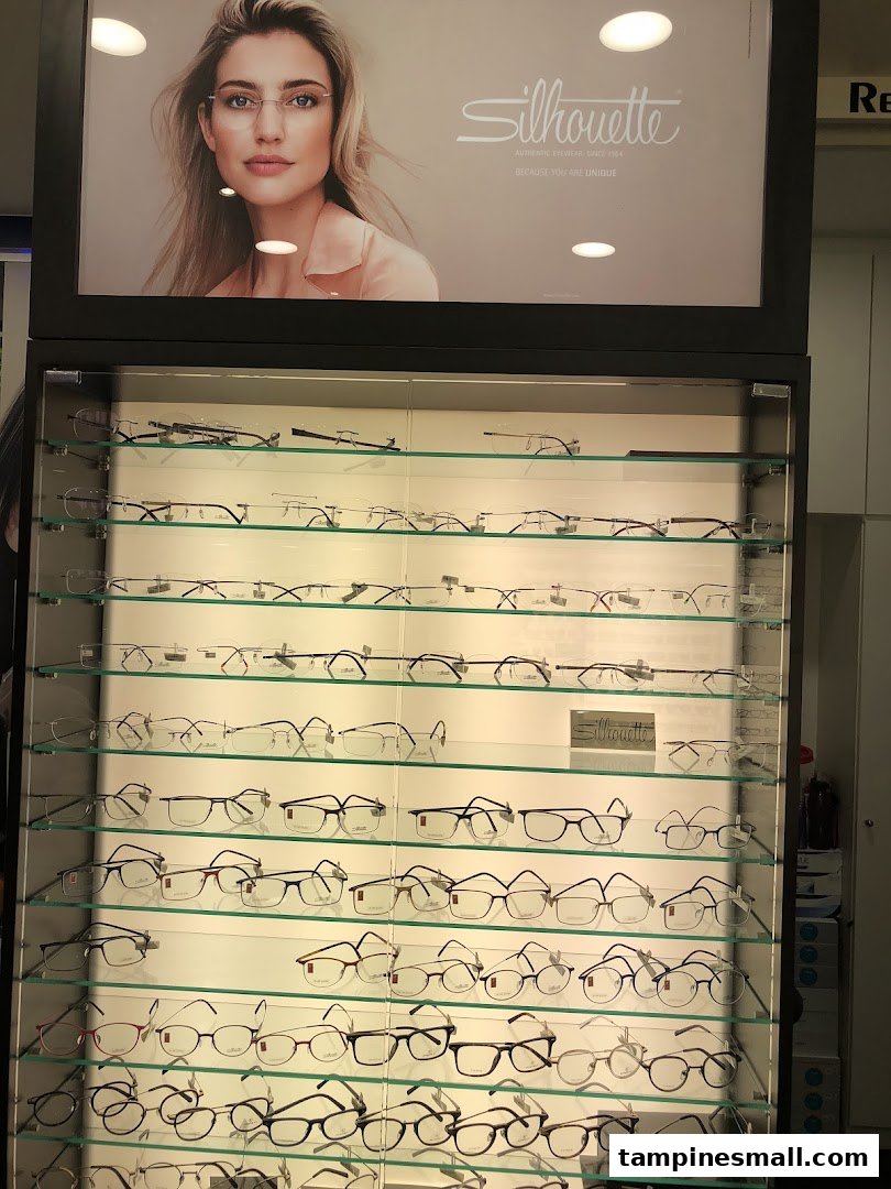 A brightly lit display case showcasing numerous pairs of eyeglasses, with a 'Silhouette' brand advertisement above.