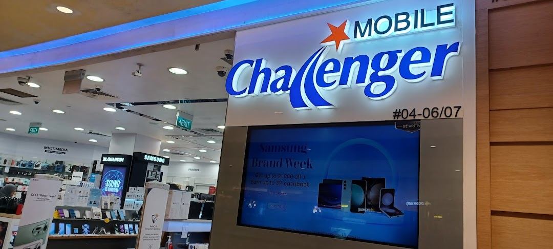 The brightly lit entrance of Challenger electronics store, featuring a large digital display with promotions.