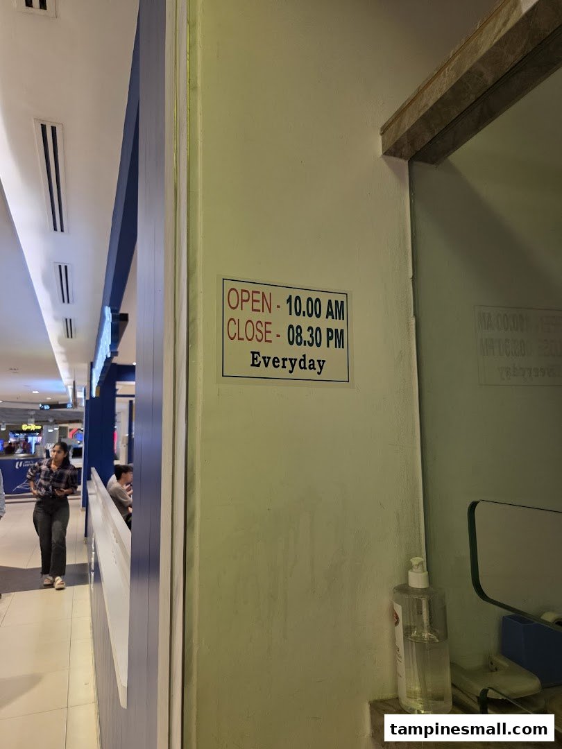 A sign displaying Chandra Money Exchange's daily operating hours within the mall environment.