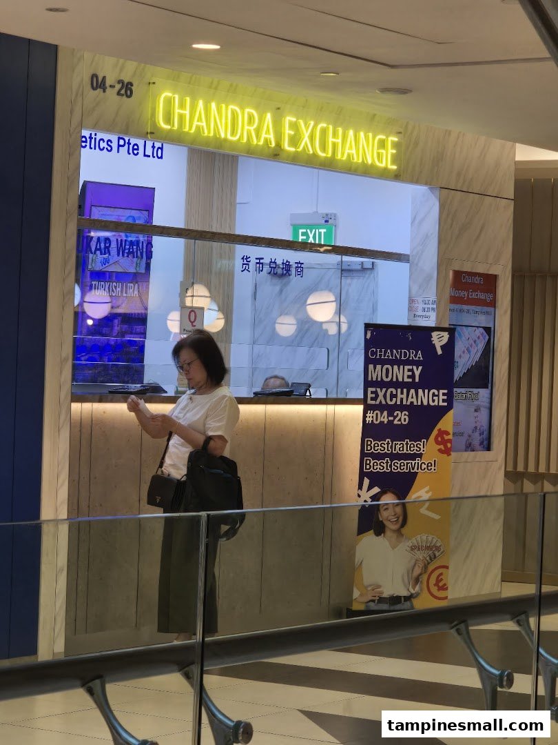 The image captures the brightly lit storefront of Chandra Money Exchange, featuring a customer at the counter.