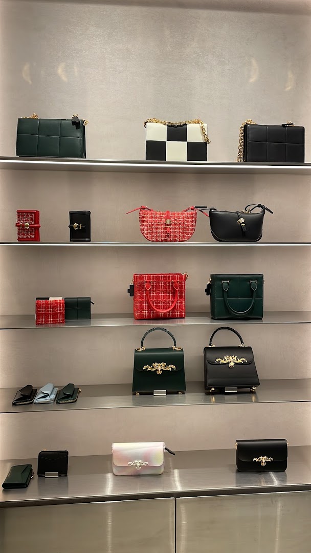A display of stylish handbags and wallets on multiple shelves inside a retail store.