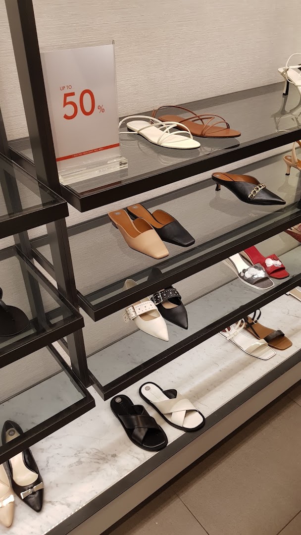 A display of various stylish shoes and sandals on shelves, with an 'Up to 50%' sale sign visible.