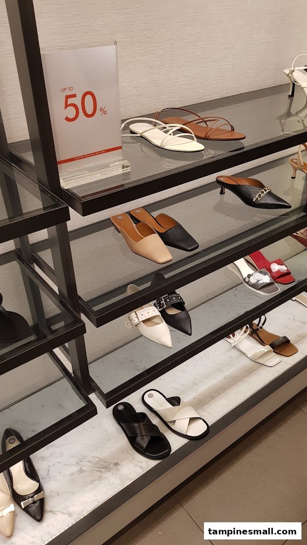 A display of various stylish shoes and sandals on shelves, with an 'Up to 50%' sale sign visible.