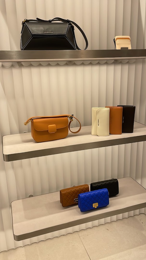 Stylish bags and wallets displayed on illuminated shelves in a CHARLES & KEITH store.