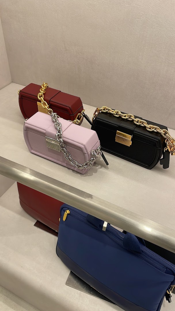 Stylish handbags in various colors displayed on shelves in a CHARLES & KEITH store.