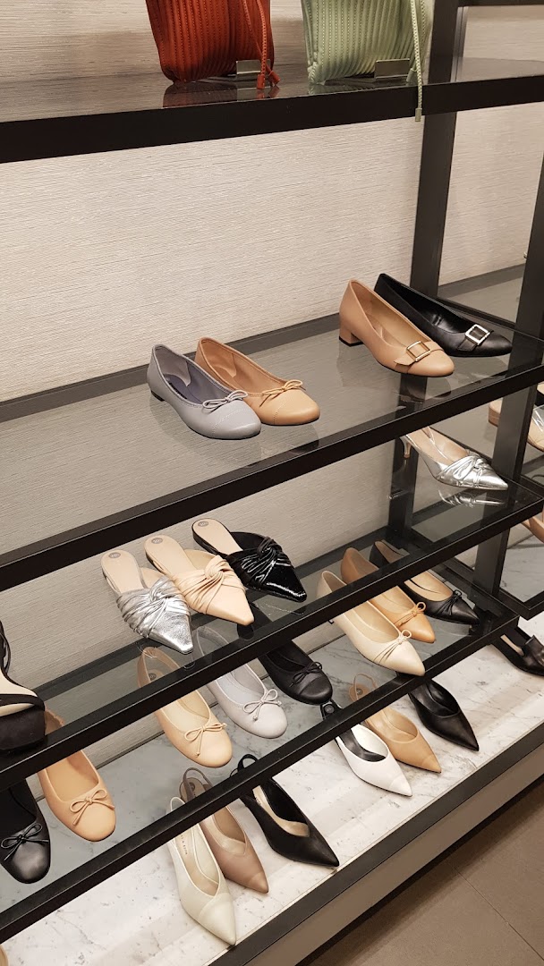 A display of various women's shoes and handbags in neutral tones on shelves.