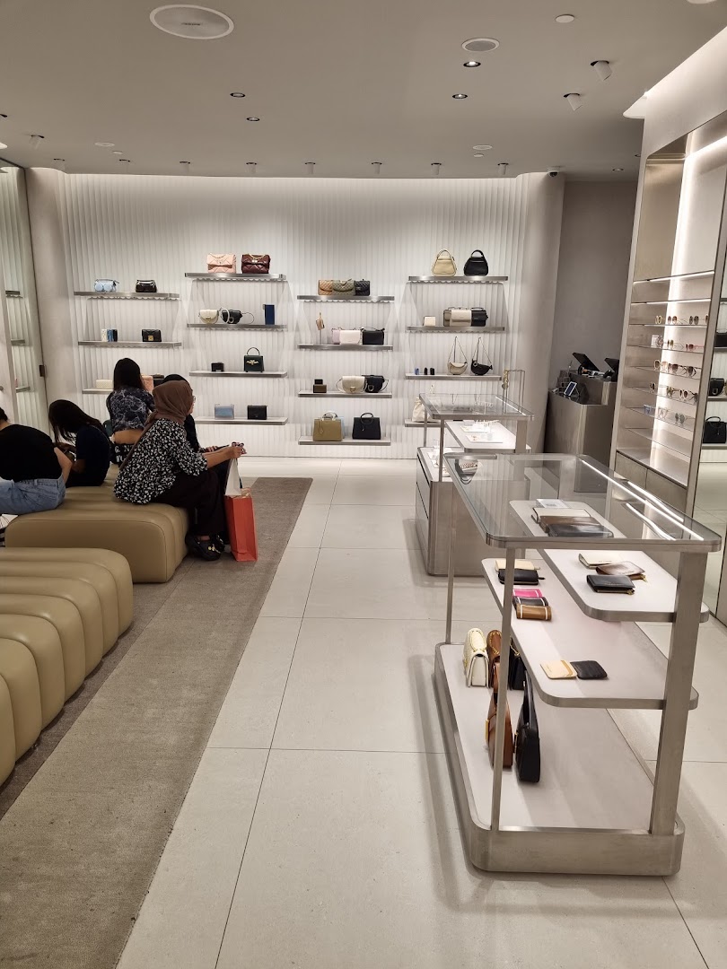 Interior view of a CHARLES & KEITH store showcasing stylish handbags, wallets, and accessories on display, with customers browsing.