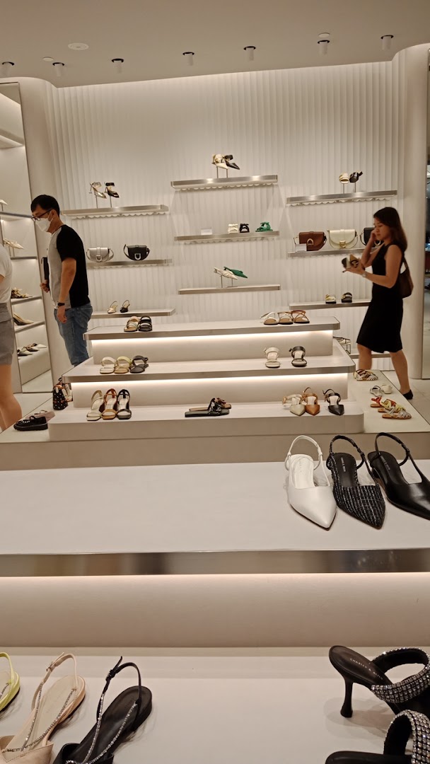 Interior view of CHARLES & KEITH store showcasing shoes and bags on modern displays with customers browsing.
