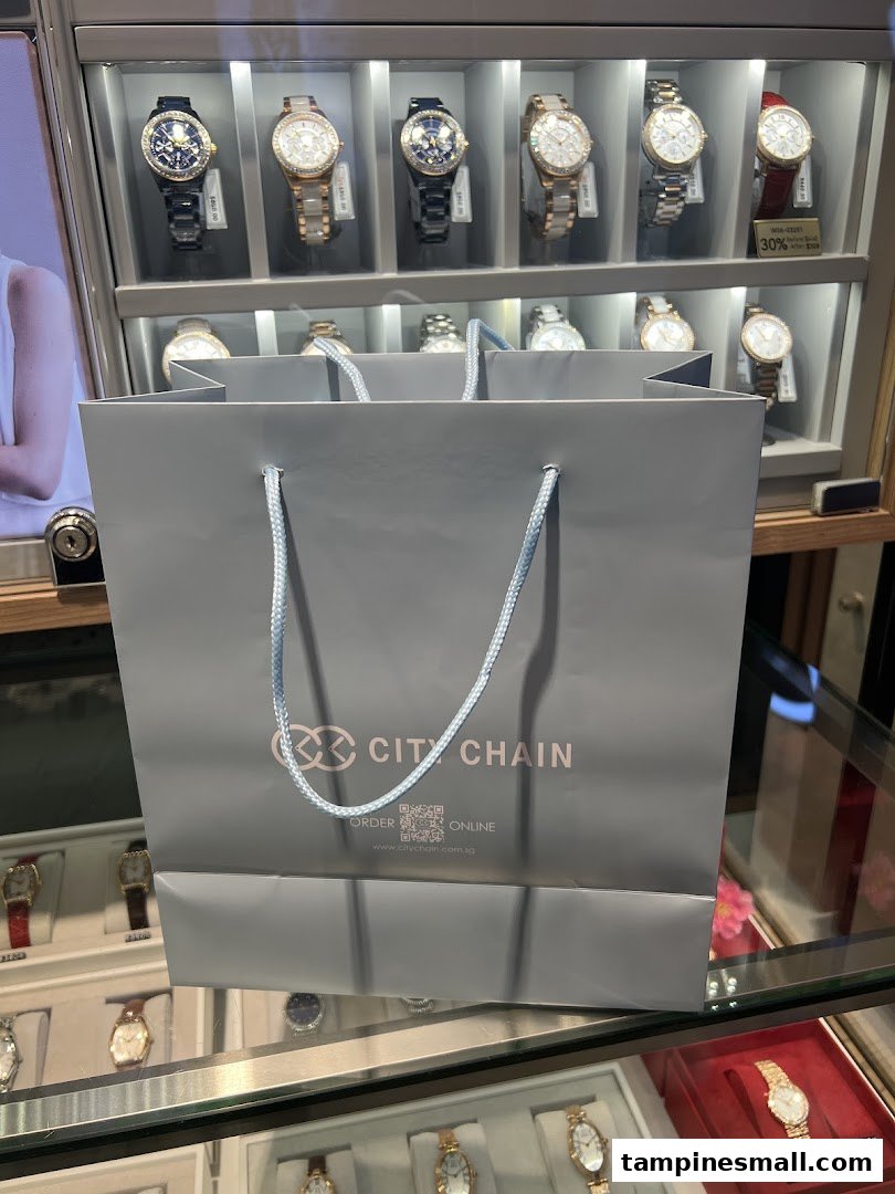 A City Chain shopping bag in front of a display case filled with various stylish watches.