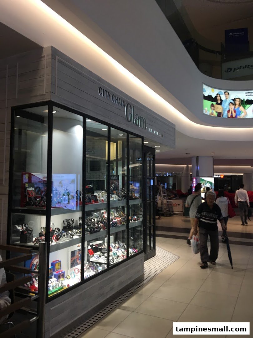 The illuminated storefront of City Chain Glam, showcasing a wide array of watches and accessories in a mall.