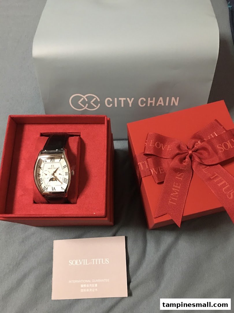 A Solvil et Titus watch in its red gift box with guarantee, alongside a City Chain shopping bag.