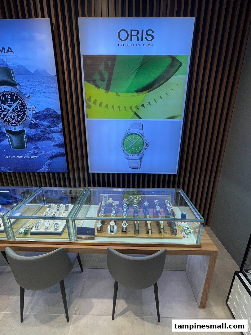 Interior view of City Chain featuring watch display cases and brand advertisements for Oris and Cyma.