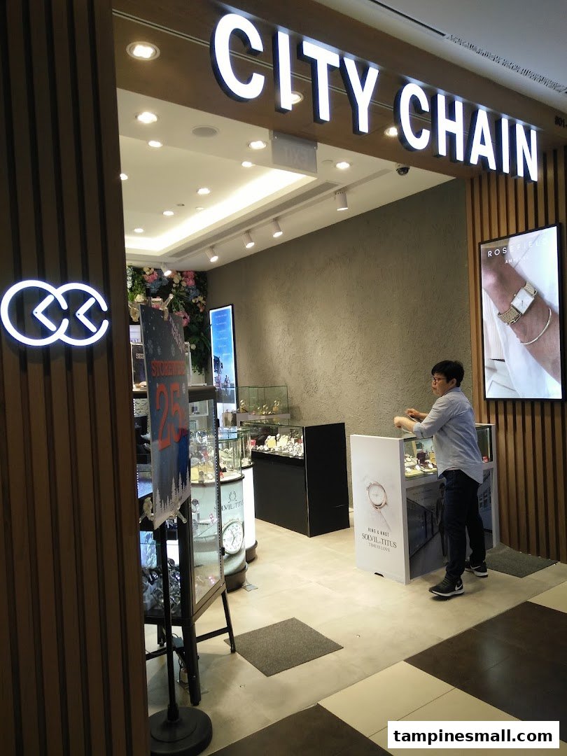 The brightly lit entrance of City Chain, a watch and eyewear store, with a staff member inside.