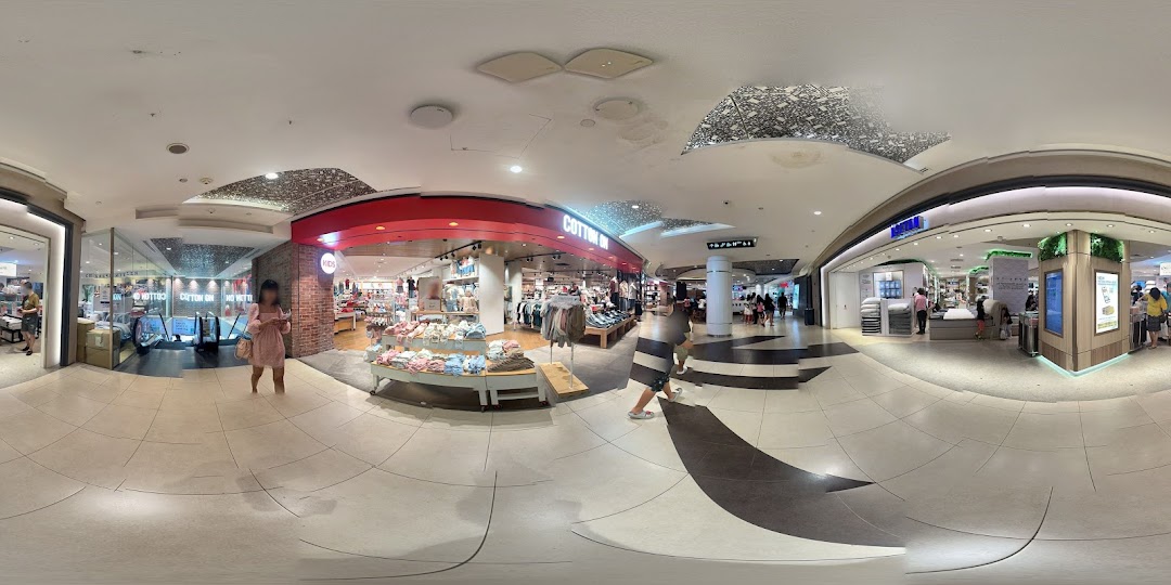 The vibrant entrance of Cotton On Tampines, showcasing fashion displays and shoppers within a bustling mall.
