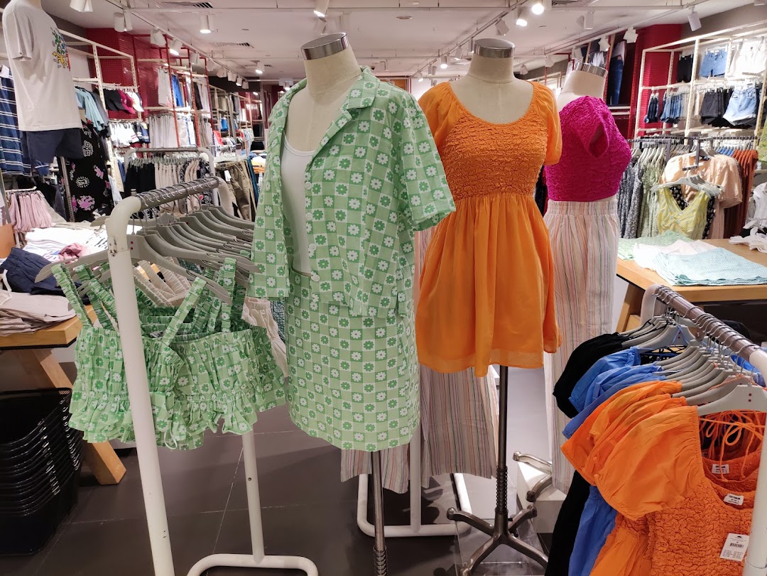 Mannequins display colorful clothing inside a Cotton On store, surrounded by racks of apparel.