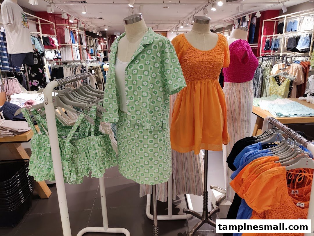 Mannequins display colorful clothing inside a Cotton On store, surrounded by racks of apparel.