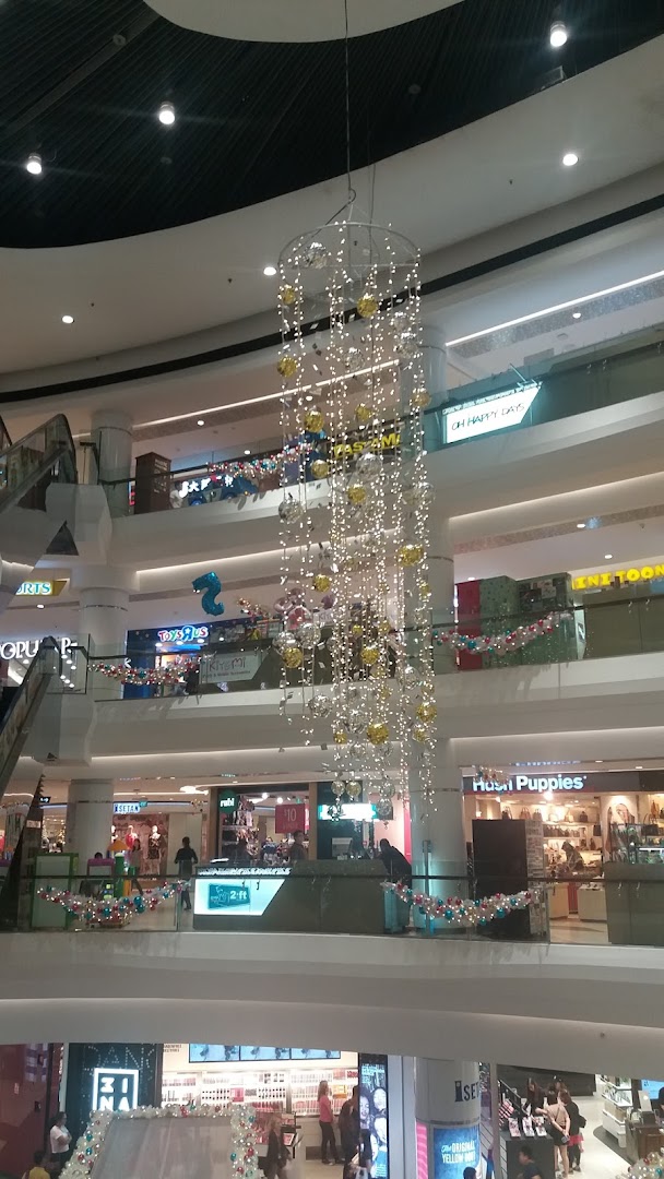 A vibrant multi-level shopping mall interior adorned with festive lights and decorations, showcasing various retail stores.