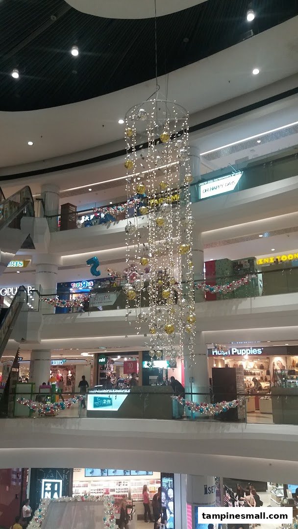 A vibrant multi-level shopping mall interior adorned with festive lights and decorations, showcasing various retail stores.