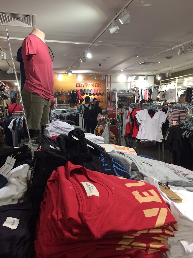 An interior view of Cotton On, showcasing clothing displays, mannequins, and customers browsing apparel.