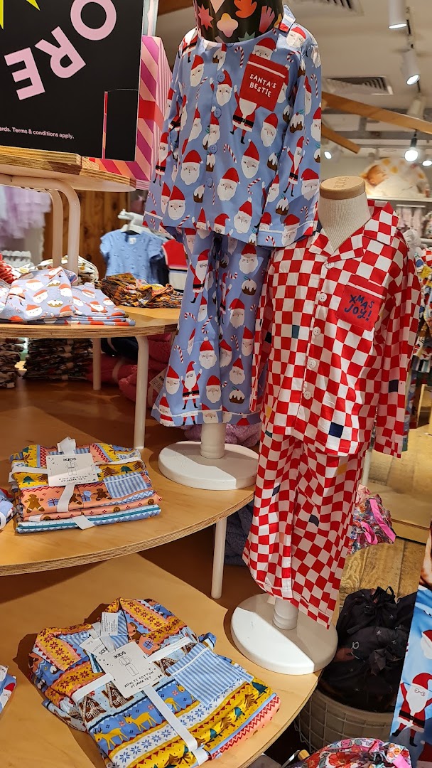 A vibrant display of festive pajamas for kids and adults, featuring Santa and checkered patterns, inside Cotton On.