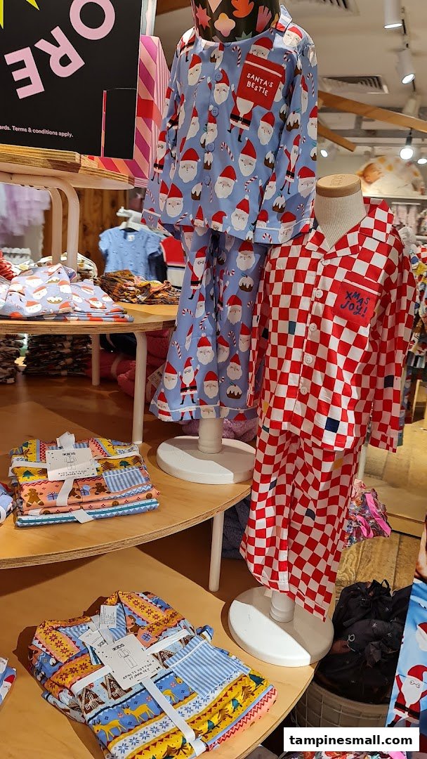 A vibrant display of festive pajamas for kids and adults, featuring Santa and checkered patterns, inside Cotton On.