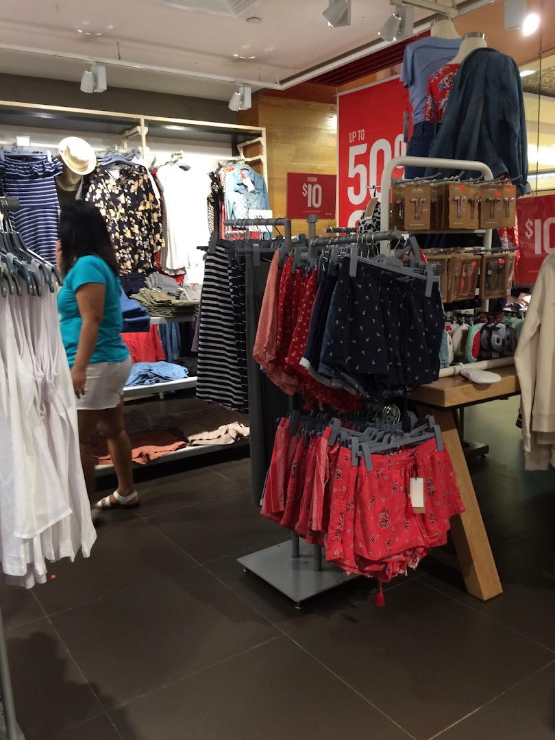 Interior view of Cotton On Tampines, showcasing clothing racks, sale items, and a shopper browsing.