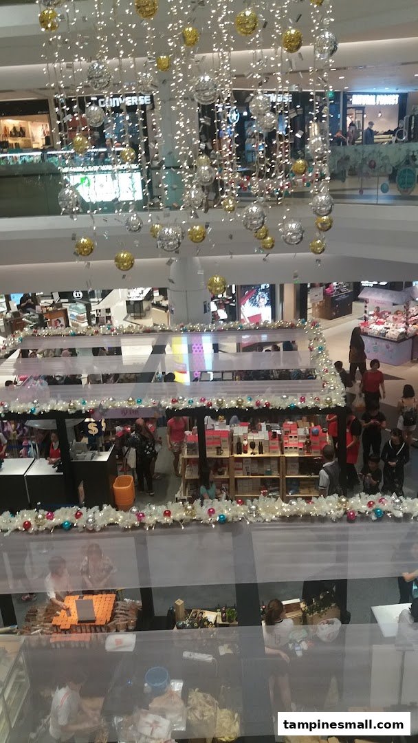 An overhead view of a bustling multi-level shopping mall interior adorned with festive holiday decorations.