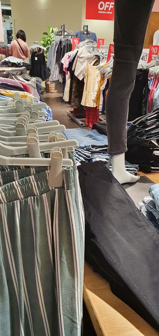 Interior view of Cotton On, showcasing clothing racks, a mannequin, and a customer browsing apparel.