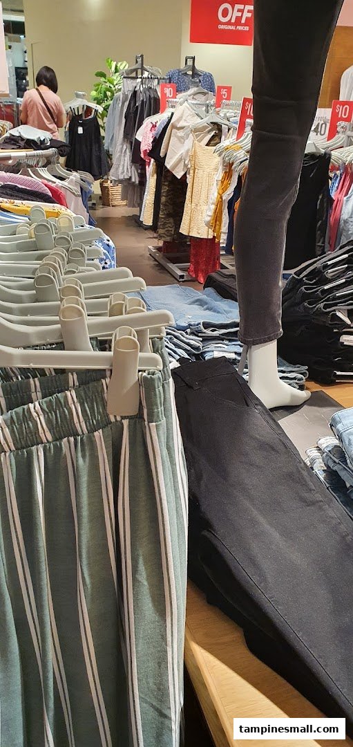 Interior view of Cotton On, showcasing clothing racks, a mannequin, and a customer browsing apparel.