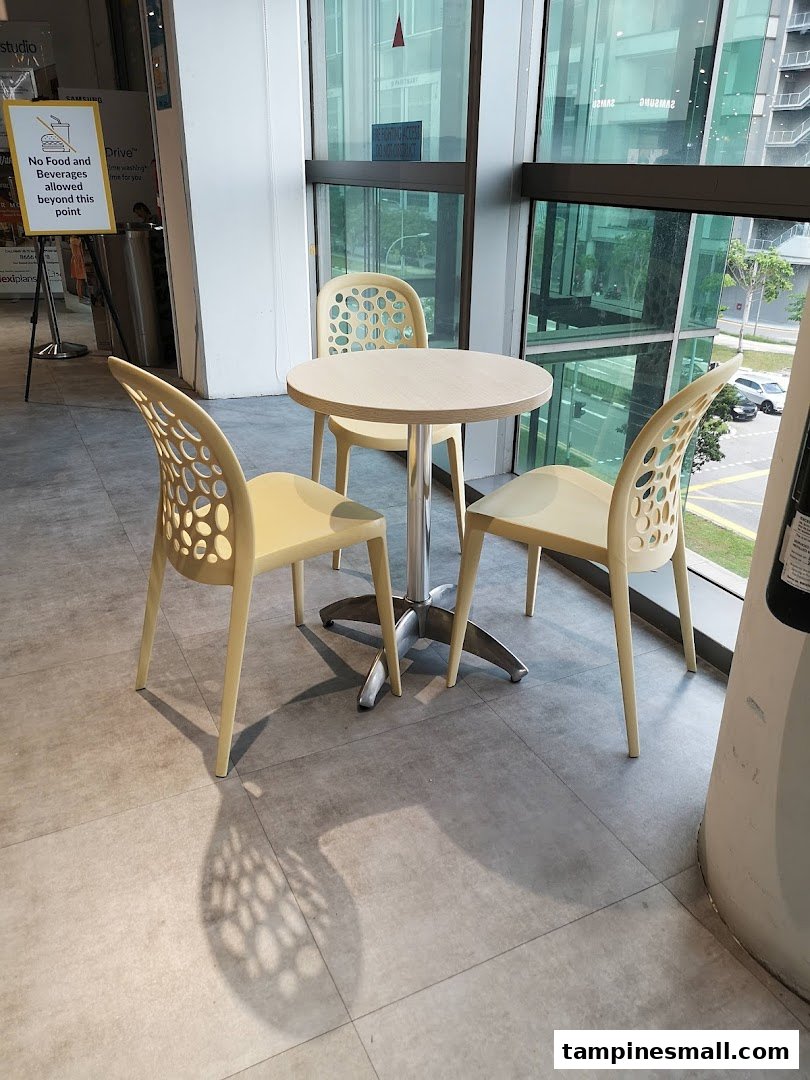 A cozy seating area with a round table and three chairs next to a large window.