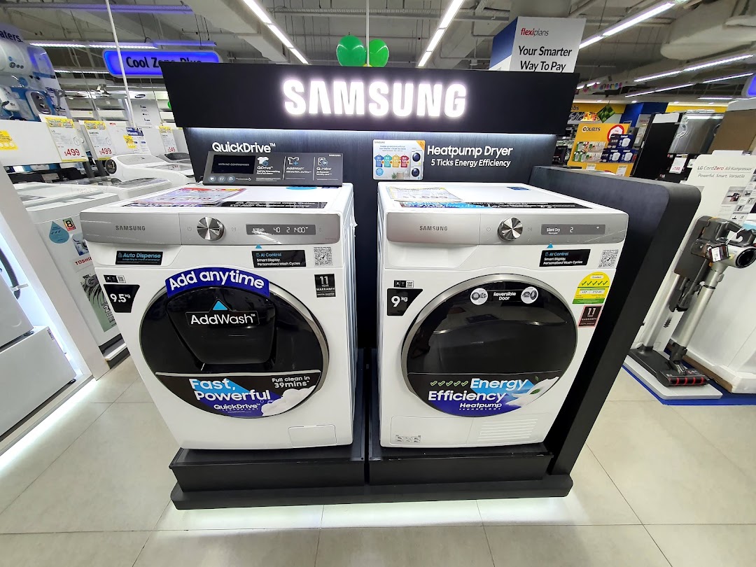 A display of Samsung washing machines and a heat pump dryer inside COURTS Tampines Mall.