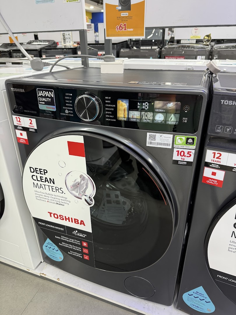 A Toshiba front-loading washing machine on display at COURTS, showcasing its features and a promotional price.