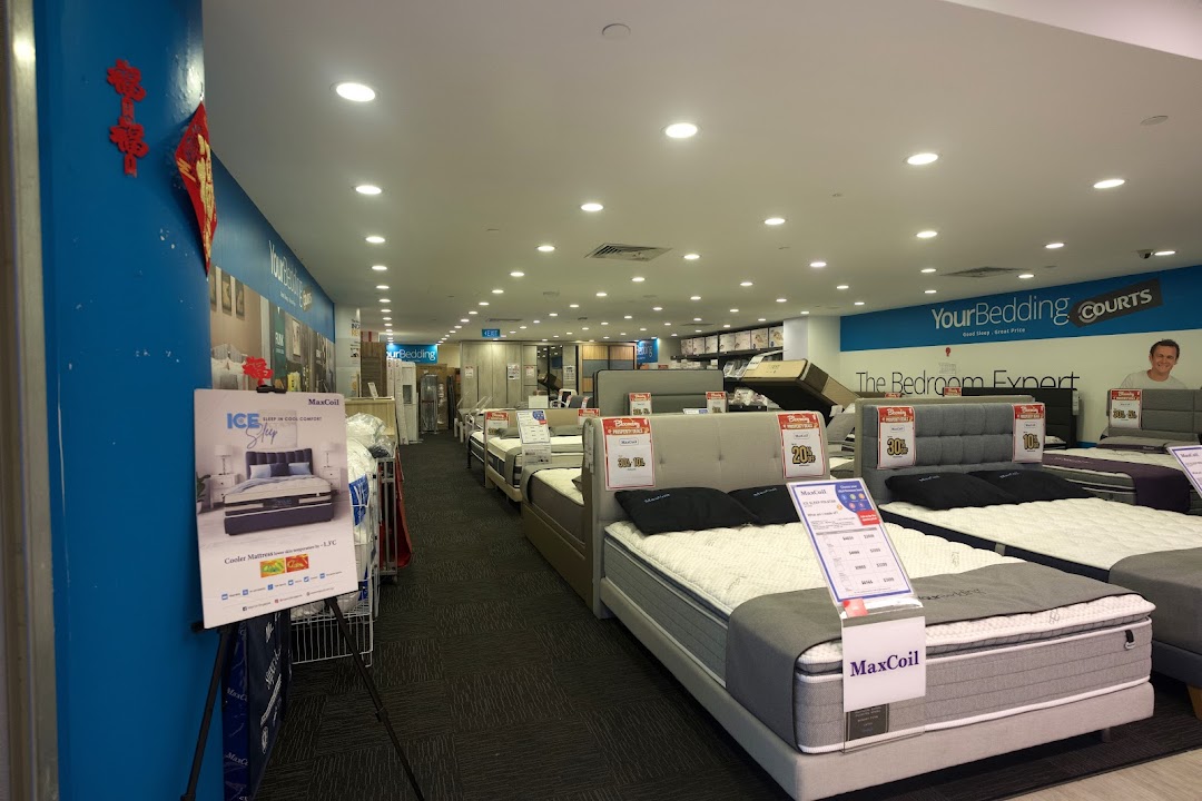 An interior view of COURTS Tampines Mall's bedding section, showcasing various mattresses and bed frames.