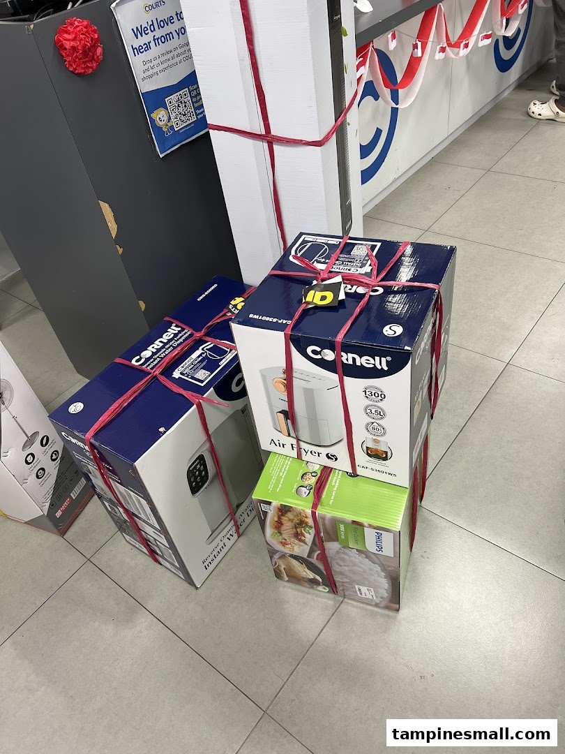 Various boxed home appliances, including Cornell air fryers and a Philips rice cooker, tied with red ribbons.