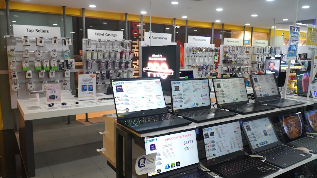Interior view of COURTS electronics store, showcasing laptops, accessories, and various tech products.