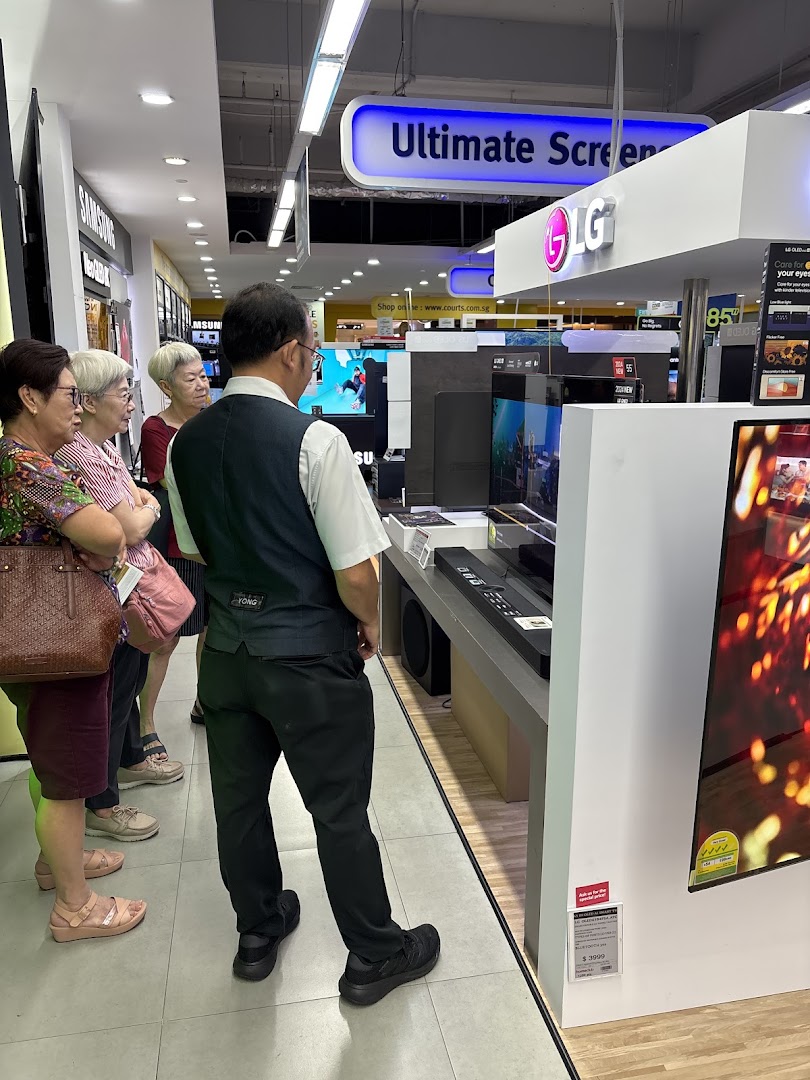 Customers browse large screen televisions and sound systems at COURTS electronics store.