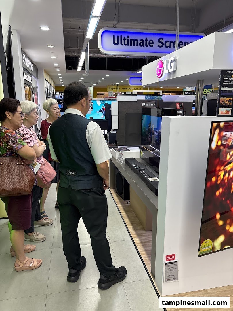 Customers browse large screen televisions and sound systems at COURTS electronics store.