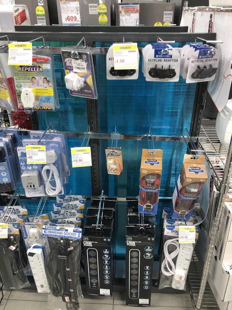 A retail display at COURTS featuring various electronic accessories like power strips, adapters, and repellents.