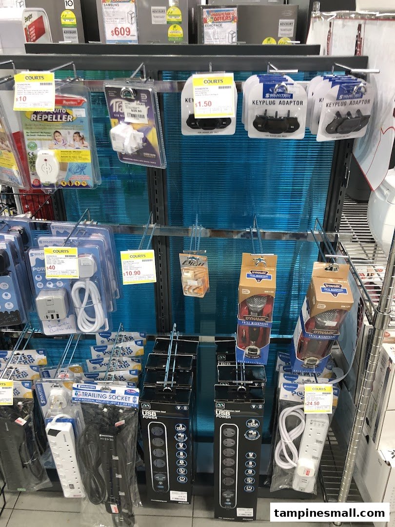 A retail display at COURTS featuring various electronic accessories like power strips, adapters, and repellents.