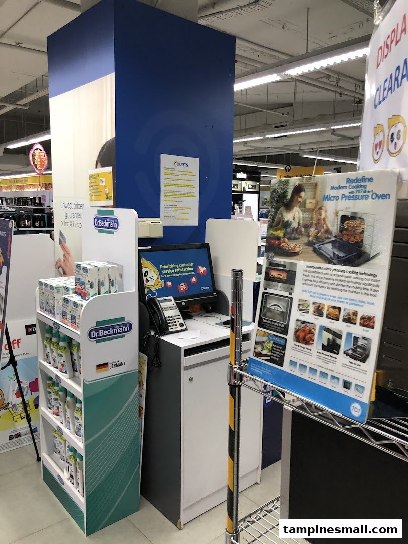 An in-store view of COURTS, featuring a customer service point, product displays, and promotional signage.