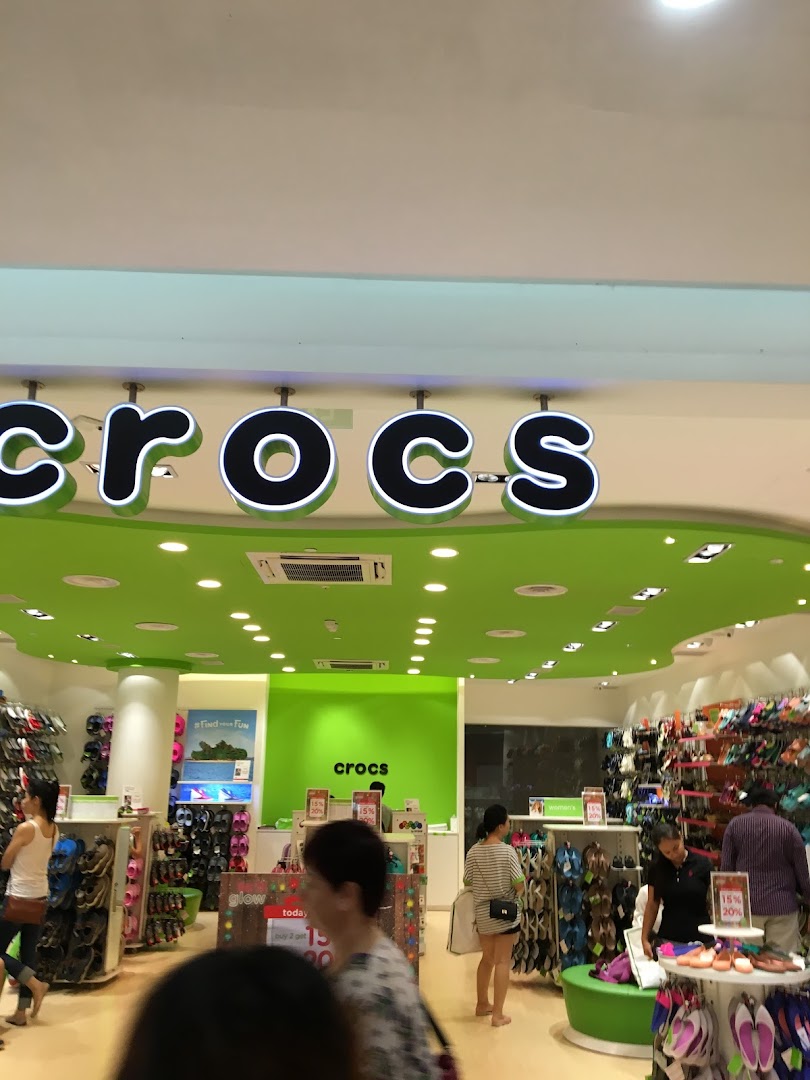 Vibrant Crocs store interior with customers browsing colorful footwear and prominent brand signage.