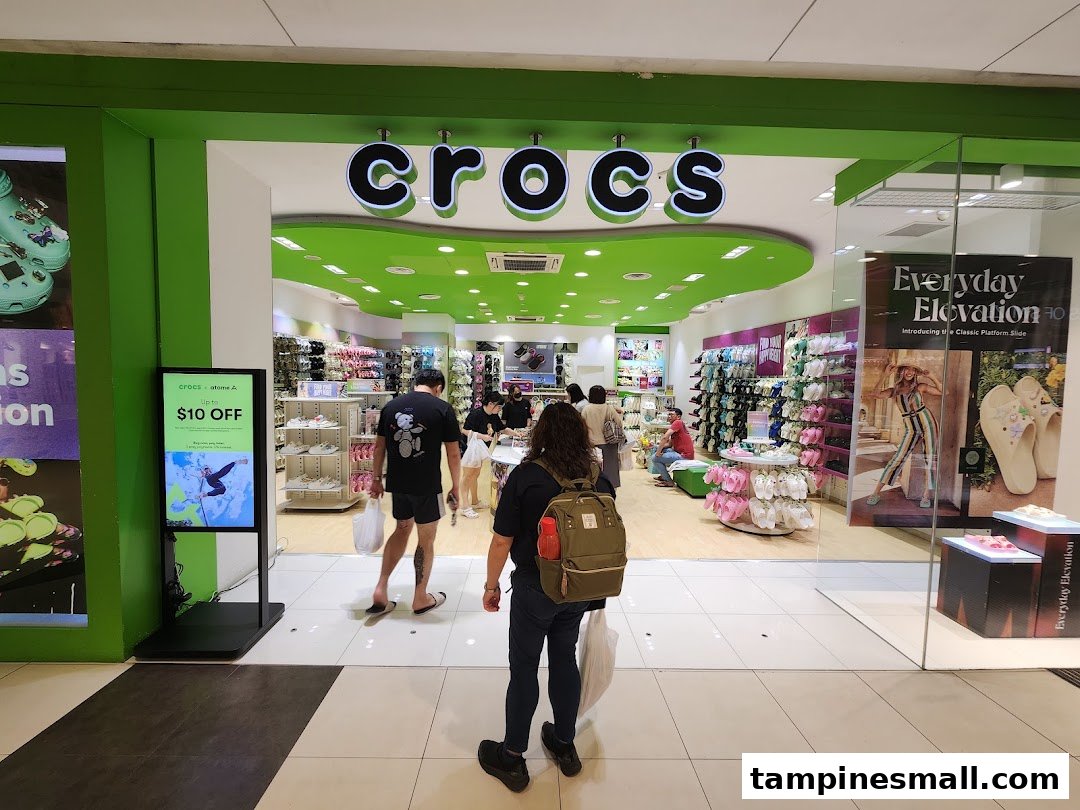 The vibrant green entrance of a Crocs store, showcasing a wide array of colorful footwear and a digital display.
