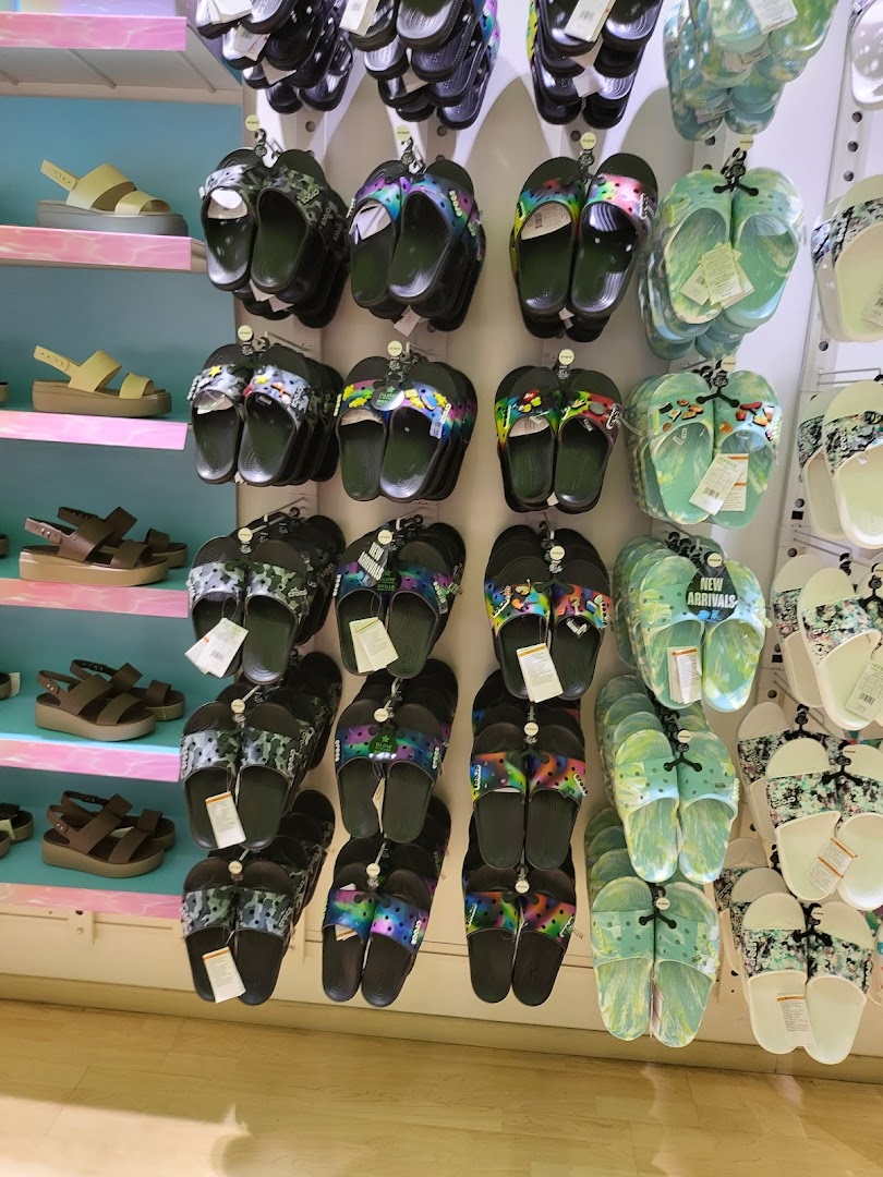 A vibrant display of Crocs sandals and slides in various colors and patterns.