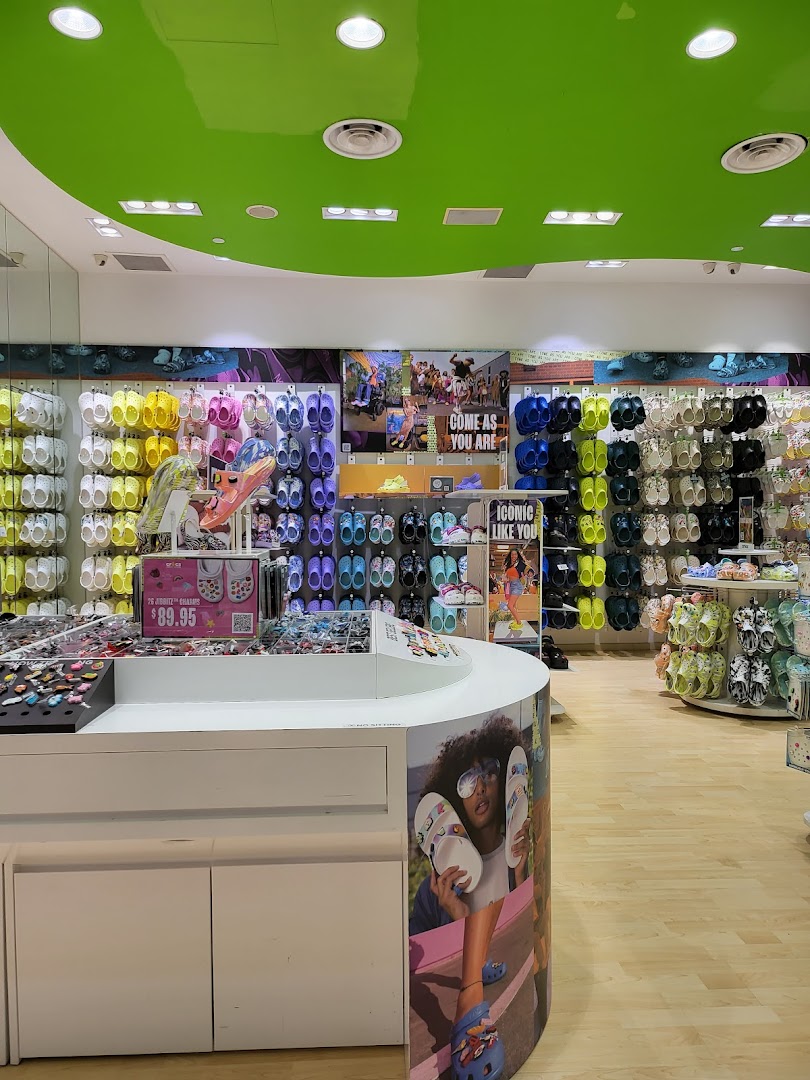 Vibrant interior of a Crocs store showcasing colorful clogs, sandals, and Jibbitz charms on display.