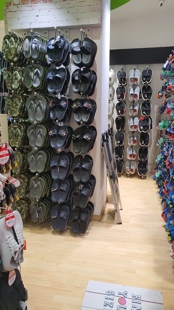 Interior view of a Crocs store showcasing various styles of sandals, flip-flops, and clogs on display.