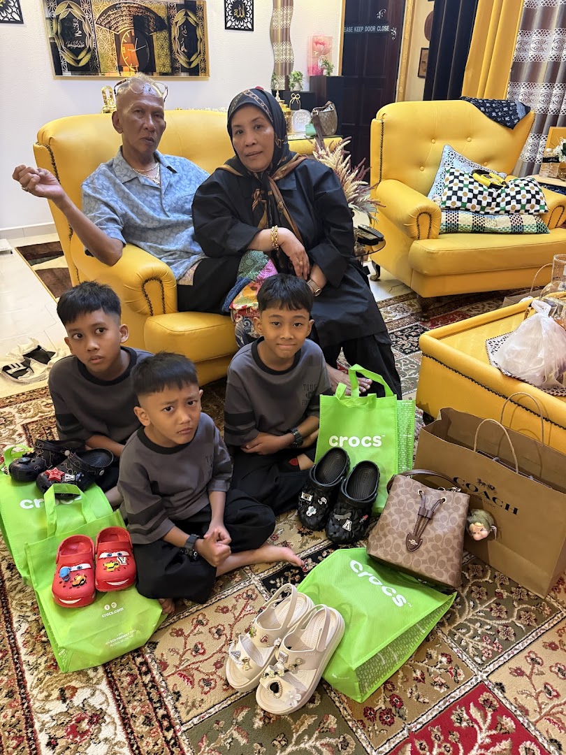 A family, including adults and children, with new Crocs shoes and shopping bags in a living room.